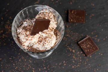 white creamy ice cream with pieces and crumbs of chocolate in a glass bowl