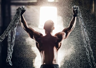 Man freeing himself from thick chains with intense white light entering dark warehouse