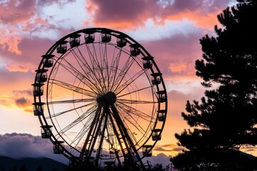 An old, rusted Ferris wheel silhouetted at sunset in the park, surrounded by trees and nature. As evening falls, the sky is painted with pinks and oranges Stock Image