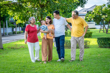 Obraz premium Asian family and baby are in the grass. Everyone looks happy.