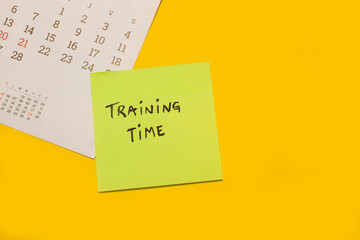 Concepto de tiempo de entrenamiento escrito en un post it junto a un calendario sobre un fondo...