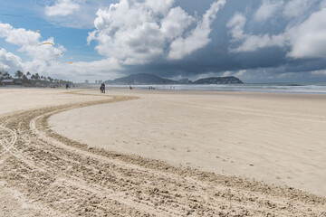 Morning at Enseada Beach on a beautiful sunny day with some rain clouds around, view of the beach sand and the sea. Guaruja - SP, Brazil.