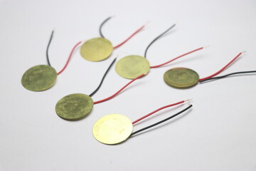 Piezoelectric discs with wires soldered made of copper on a white background