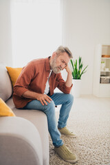 Vertical full size photo of senior male sit couch suffer grief depressed dressed brown outfit cozy...