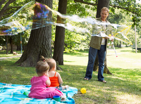Father Blowing Bubbles while Babies Watch