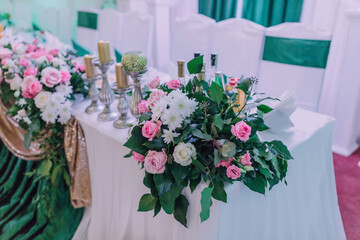 A table with a floral arrangement and candles on it. The table is set for a special occasion