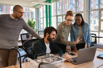 Focused group of diverse businesspeople working together on a laptop