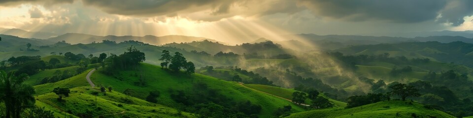 Fototapeta premium A majestic rural hill scene with sunbeams through a cloudscape over lush pastures and forests.