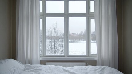 Fototapeta premium The serene bedroom features white bedding and a window displaying a snowy tree, encapsulating a tranquil winter atmosphere with light gray tones