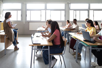 Female caucasian teacher explaining lesson to multiracial high school students