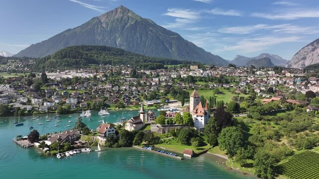 Aerial view of Lake Thunersee in Spiez, Kanton Bern, Switzerland, showcasing a charming town nestled near the lake with a majestic mountainous backdrop.