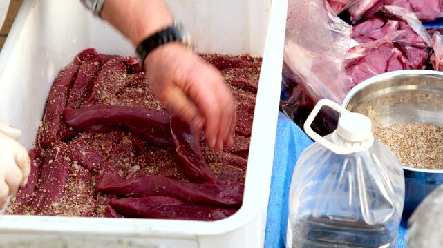 Stacking venison steak strips to be cured and spiced for South African biltong