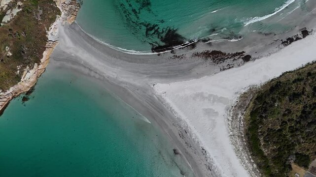 Diamond Island connected with Tasmanian Coastline in summer. Sandy sandbank between both. Indian turquoise ocean water with waves. Aerial top down shot.