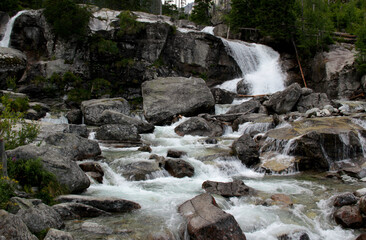 Landscape photo of the part of Vodopady Studeneho potoka waterfall against a background of pine trees in Vysoke Tatry region, Slovakia	