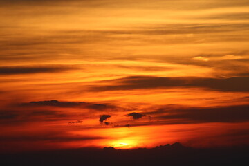 The sun setting behind the clouds. Orange sky. Amazing sunset