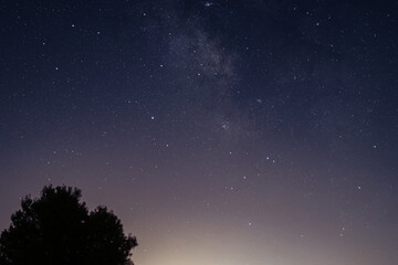 The milky way galaxy stretches across starry night sky with gradient of dark blue, purple, and orange completing scene