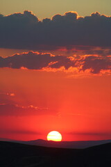 The sun setting behind the clouds. Orange sky. Amazing sunset