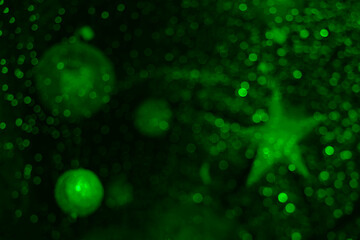 Christmas shining star, balls hang on a garland. light green Background bright blurred lights bokeh light. Merry Christmas and Happy New Year 2025 . Festive bright blur background. night evening scene