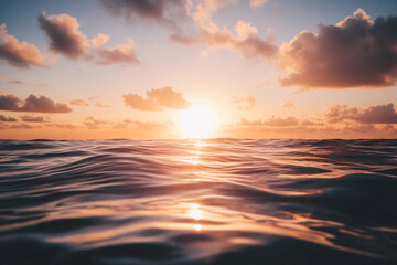 Fototapeta premium The sun is setting over the ocean, casting a warm glow on the water