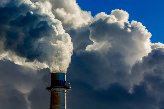 Close-up of an electrical plant's stack with large clouds of exhausts and blue sky; East of Calgary, Alberta, Canada