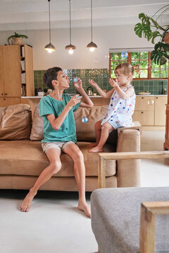 Brother (8-9) and sister (18 - 23�months)�blowing bubbles at home