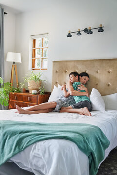 Mother and son (8-9) embracing on bed