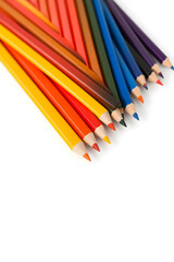 Fototapeta premium A vibrant collection of colored pencils arranged in a row, showcasing a variety of colors including red, blue, green, yellow, and orange against a white background.