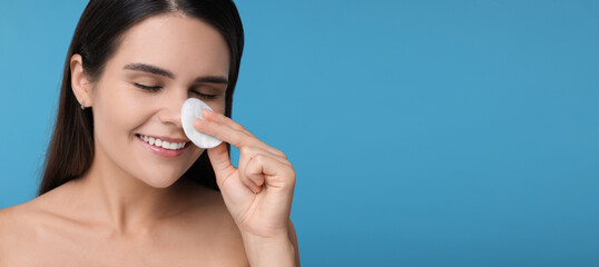 Young woman with cotton pad on light blue background. Banner design with space for text