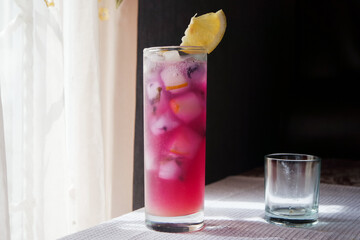 Iced Butterfly Pea Tea with Sliced Lemon. Lemonade with Butterfly Pea Tea Base in Front of Window.