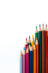 Naklejka premium A vibrant collection of colored pencils arranged in a row, showcasing a variety of colors including red, blue, green, yellow, and orange against a white background.