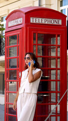 Woman near the telephone booth with cell phone, technology . High quality photo