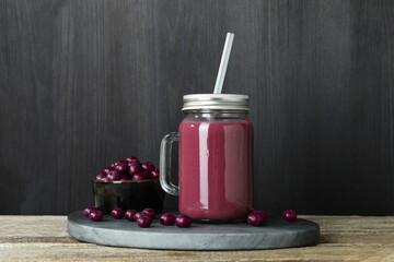 Tasty fresh acai juice in mason jar and berries on wooden table