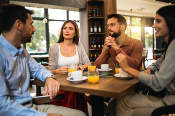 Group of friends chilling at the cafe. Talking, drinking coffee and orange juice.