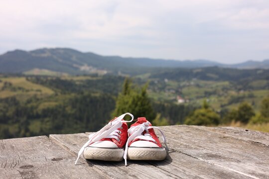 Pair of red shoes on wooden surface in mountains, space for text - Powered by Adobe