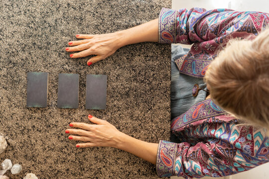 Top view of a tarot reader and three cards turned face down