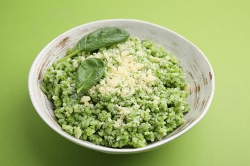 Tasty spinach risotto on light green background, closeup