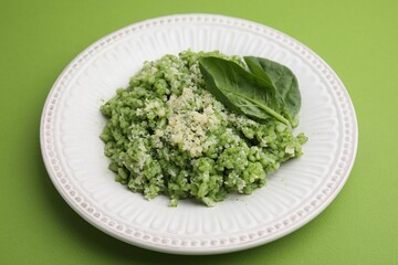 Tasty spinach risotto on light green background, closeup
