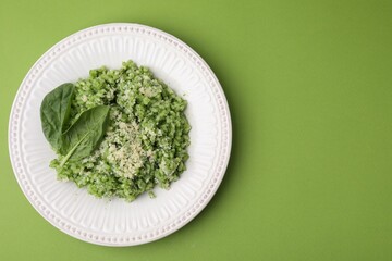 Tasty spinach risotto on light green background, top view. Space for text