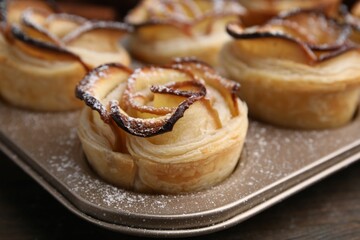 Freshly baked apple roses on wooden table, closeup. Puff pastry