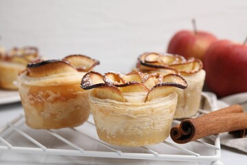 Freshly baked apple roses on white tiled table, closeup. Puff pastry