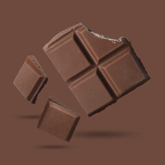 Pieces of sweet chocolate falling on brown background