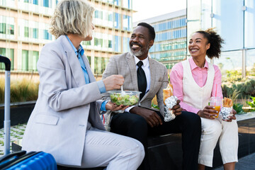 Group of multiethnic business people meeting outdoors during lunch pause from work - International...