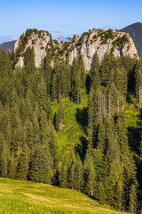 Blick vom Grünten in der Nähe der Grüntenhütte auf ein Felsmassiv in dessen Wand ein Kletterer hängt