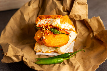 selective focus of Mumbai's famous street food delicious Vada Pav, With coriander leave chutney, tomato sauce, dry garlic chutney and fried chilli. 