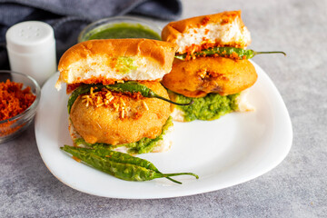 selective focus of Mumbai's famous street food delicious Vada Pav, With coriander leave chutney, tomato sauce, dry garlic chutney and fried chilli. 