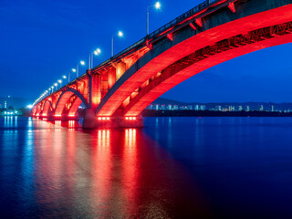 A bridge over a wide river with night illumination.