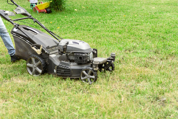 man cutting the grass with black lawnmower
