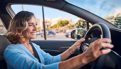 A woman is driving a car and smiling