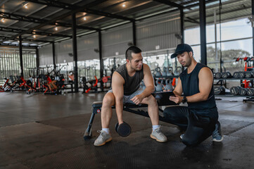 Asian man sitting on a stool with personal trainer,Hire a professional trainer to teach weight training,body and healthy cardio sports workout