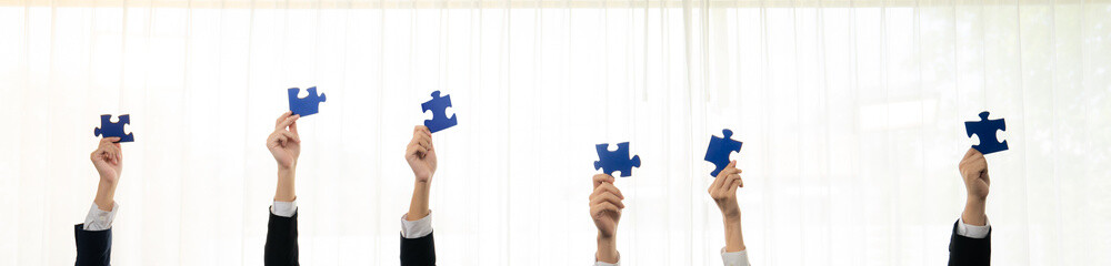 Panorama banner of business team assembling jigsaw puzzle over table symbolize business partnership...